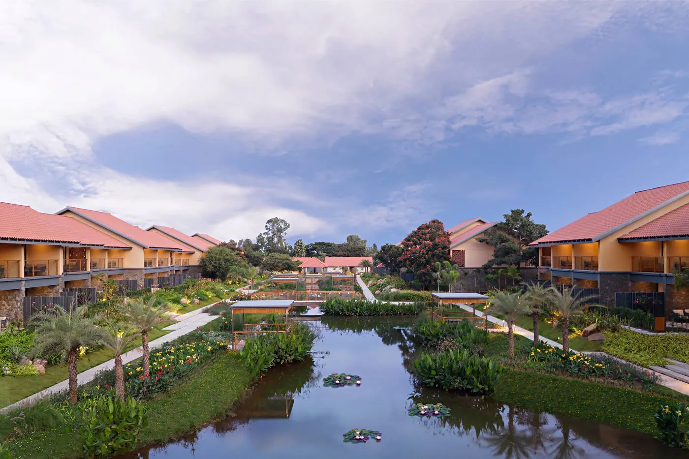 Aerial view of Hilton Hyderabad Genome Valley Resort: terracotta-roofed villas around lily ponds, palms and gardens